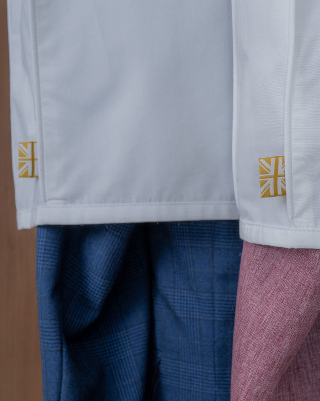 Close-up of a white dust cover with union jack label on sleeves, blue pants, and pink sweater.
