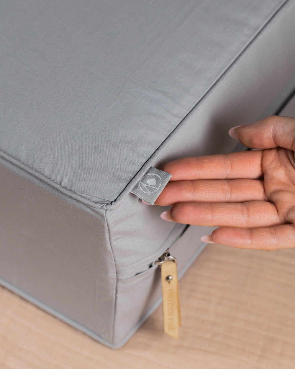 Person opening a grey clothes storage box with a zipper
