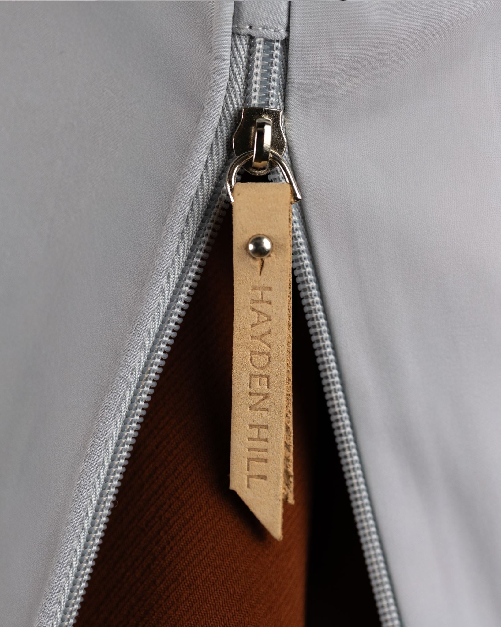 Close-up of a zipper with a 'Hayden Hill' label on a grey garment.