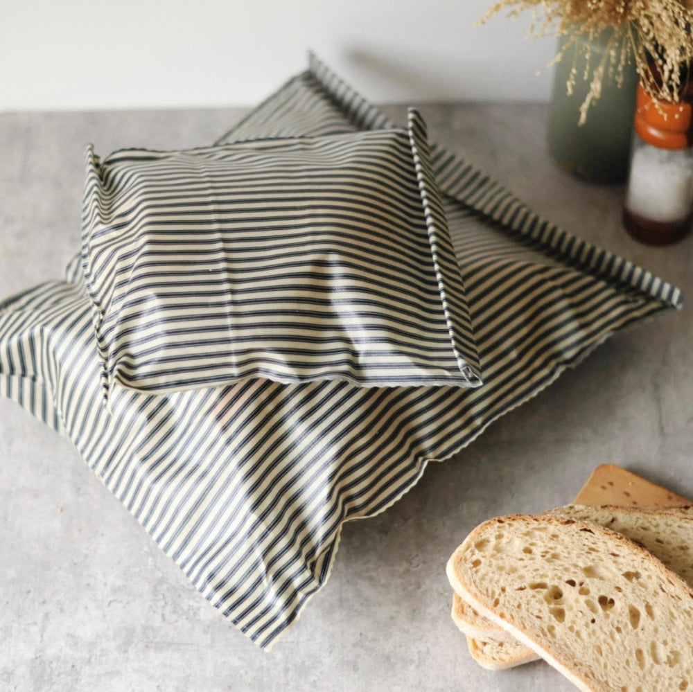 Striped cloth on a table with bread slices and a vase in the background