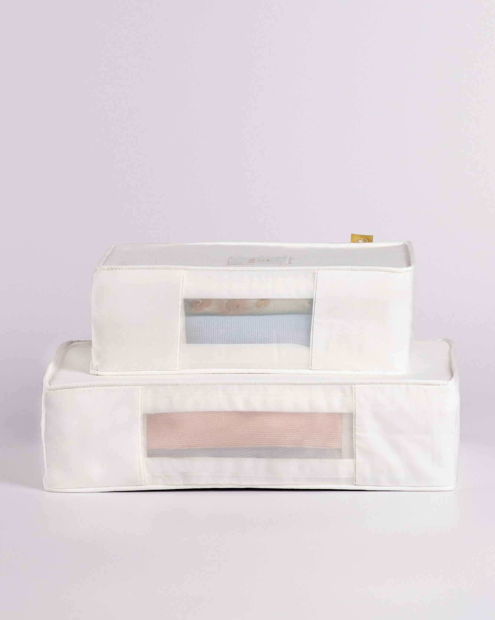 Two white fabric storage bins with clear window fronts, stacked with the smaller one on top of the larger one, on a light gray background.
