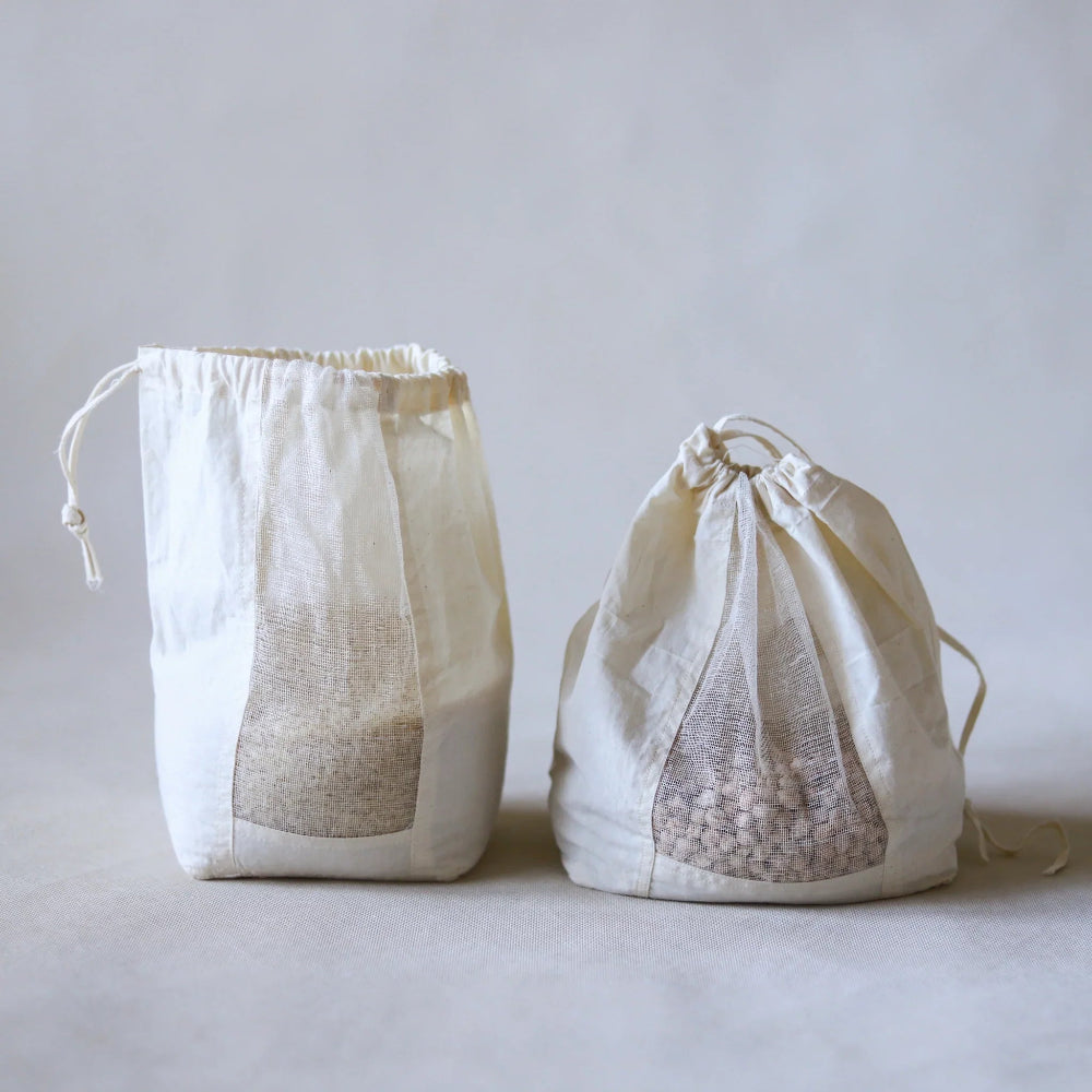 Two white drawstring bags filled with rice on a light grey background