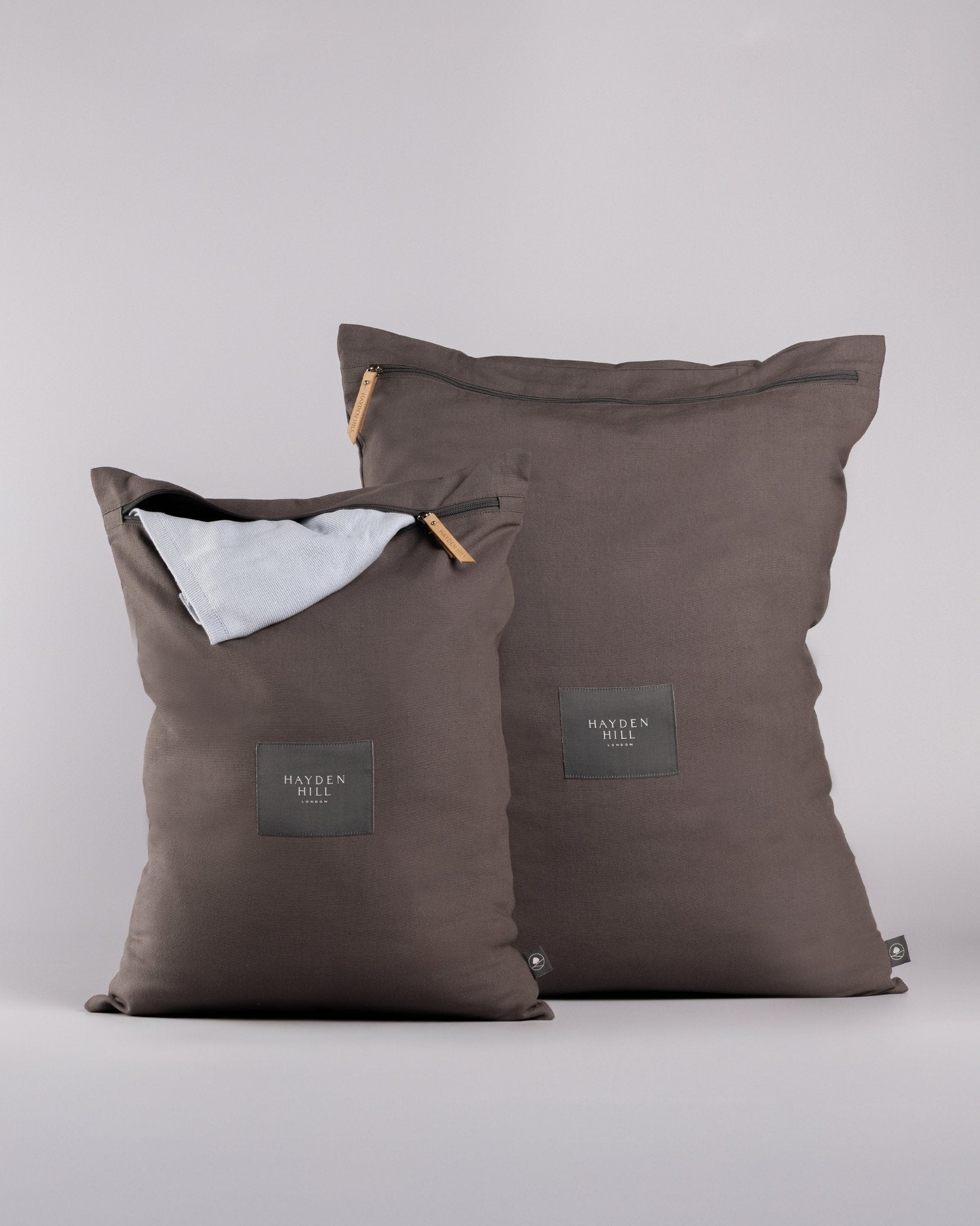 Two charcoal grey laundry bags with a visible brand label on a light grey background