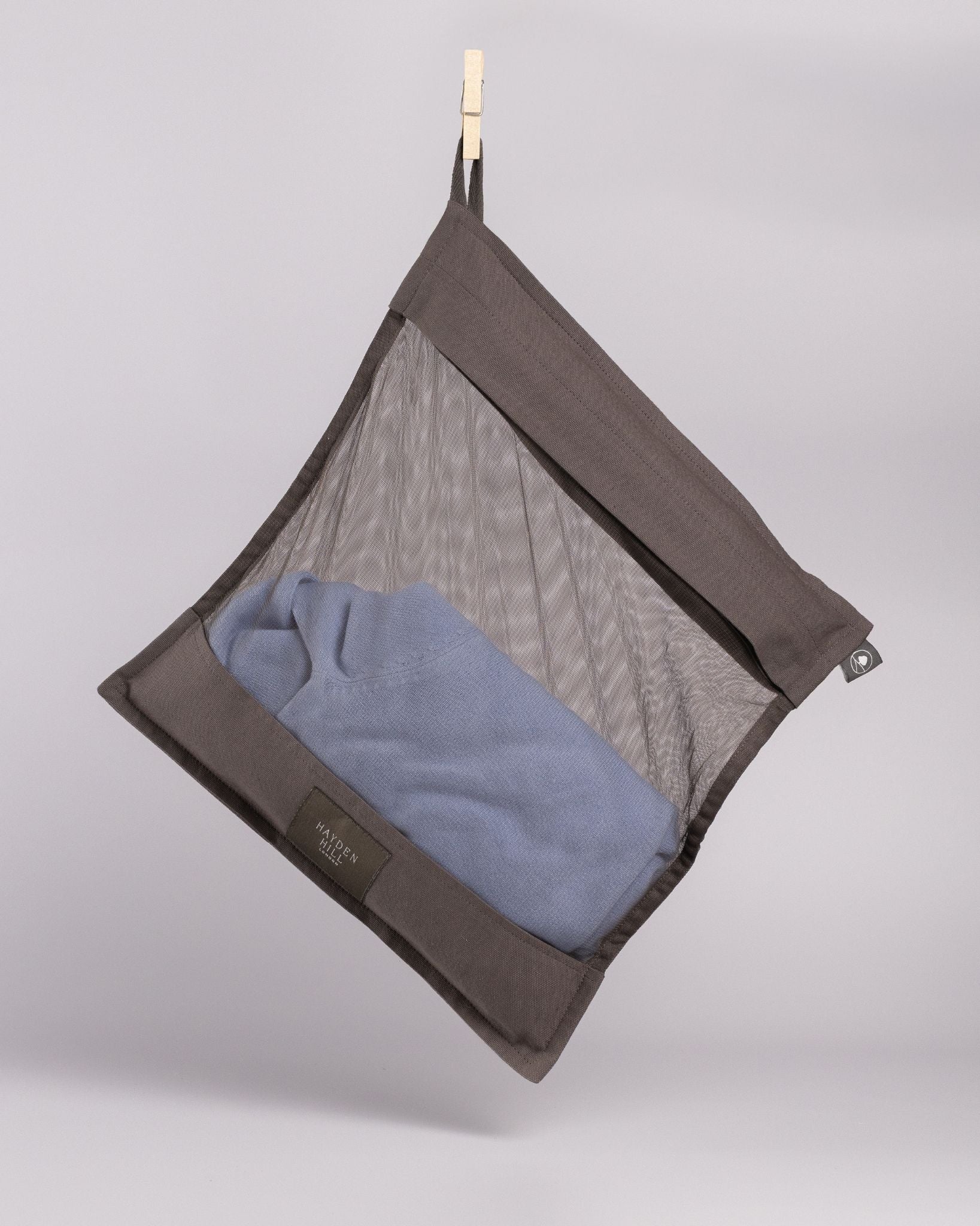 Mesh laundry bag with clothes hanging on a gray background