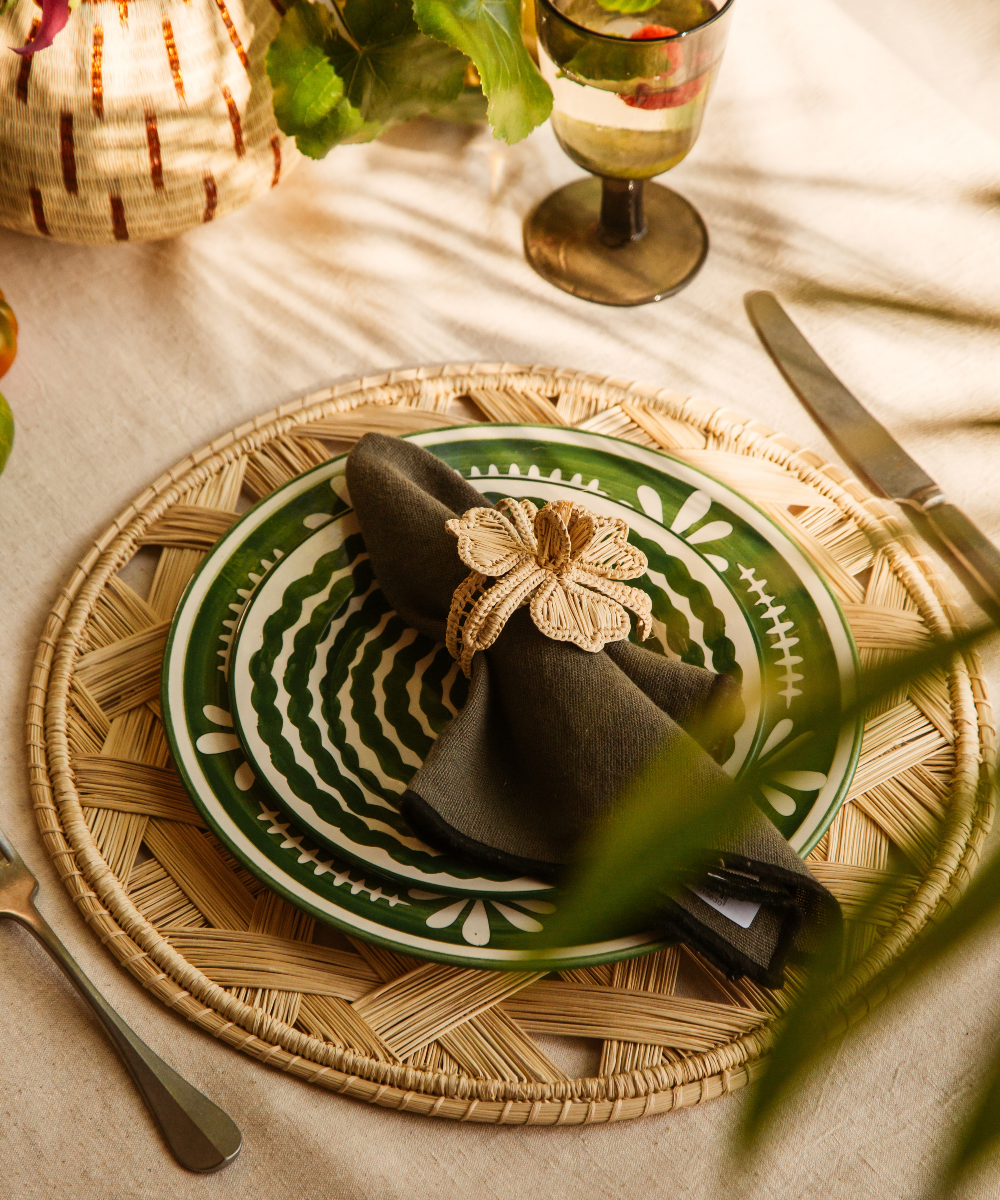 Decorative table setting with a green plate, black napkin, and woven placemat.