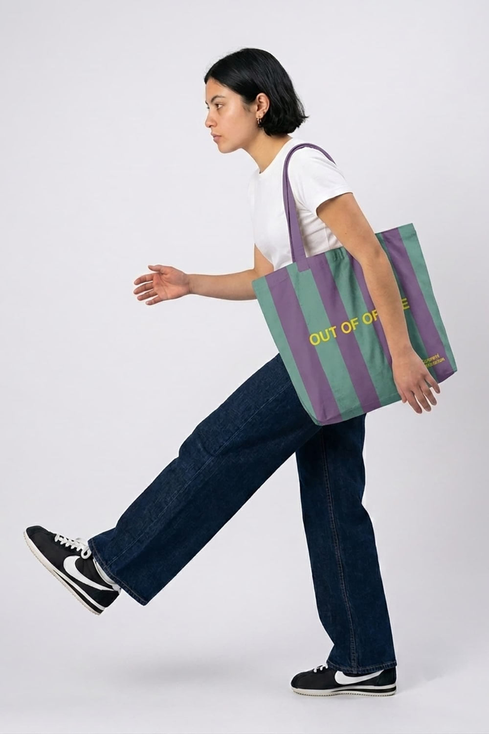 Person holding a striped tote bag with text on a white background