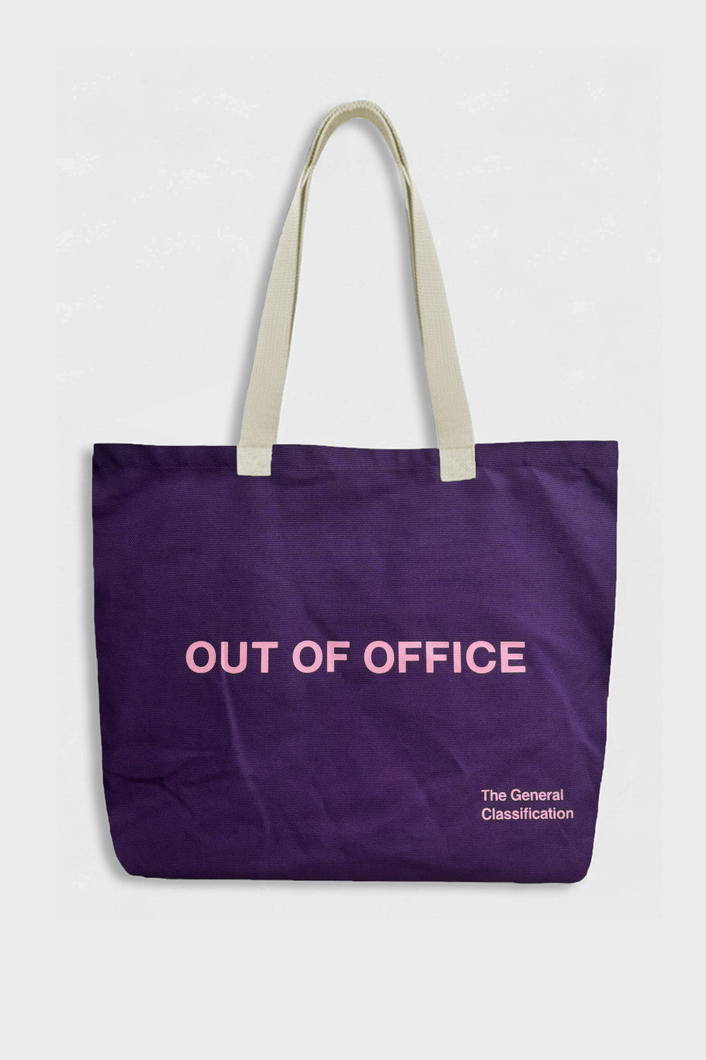 A purple canvas tote bag with cream-colored shoulder straps, featuring the words 'OUT OF OFFICE' in light pink text on the front, with a small white text print reading 'The General Classification' in the bottom right corner.
