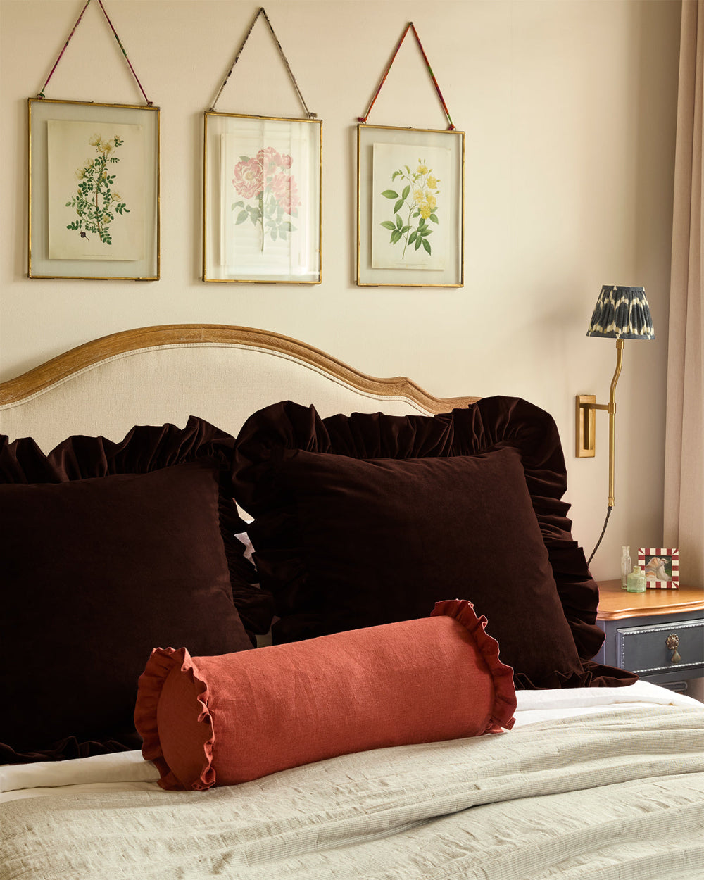 Oversized burgundy velvet cushion by Kika Bespoke styled at the head of a bed
