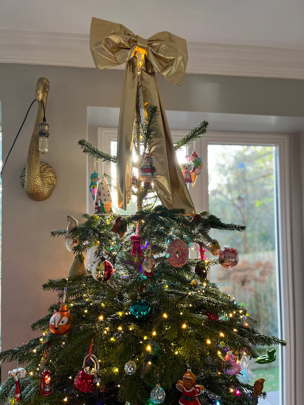 Oversized gold bow used as a statement Christmas tree decoration