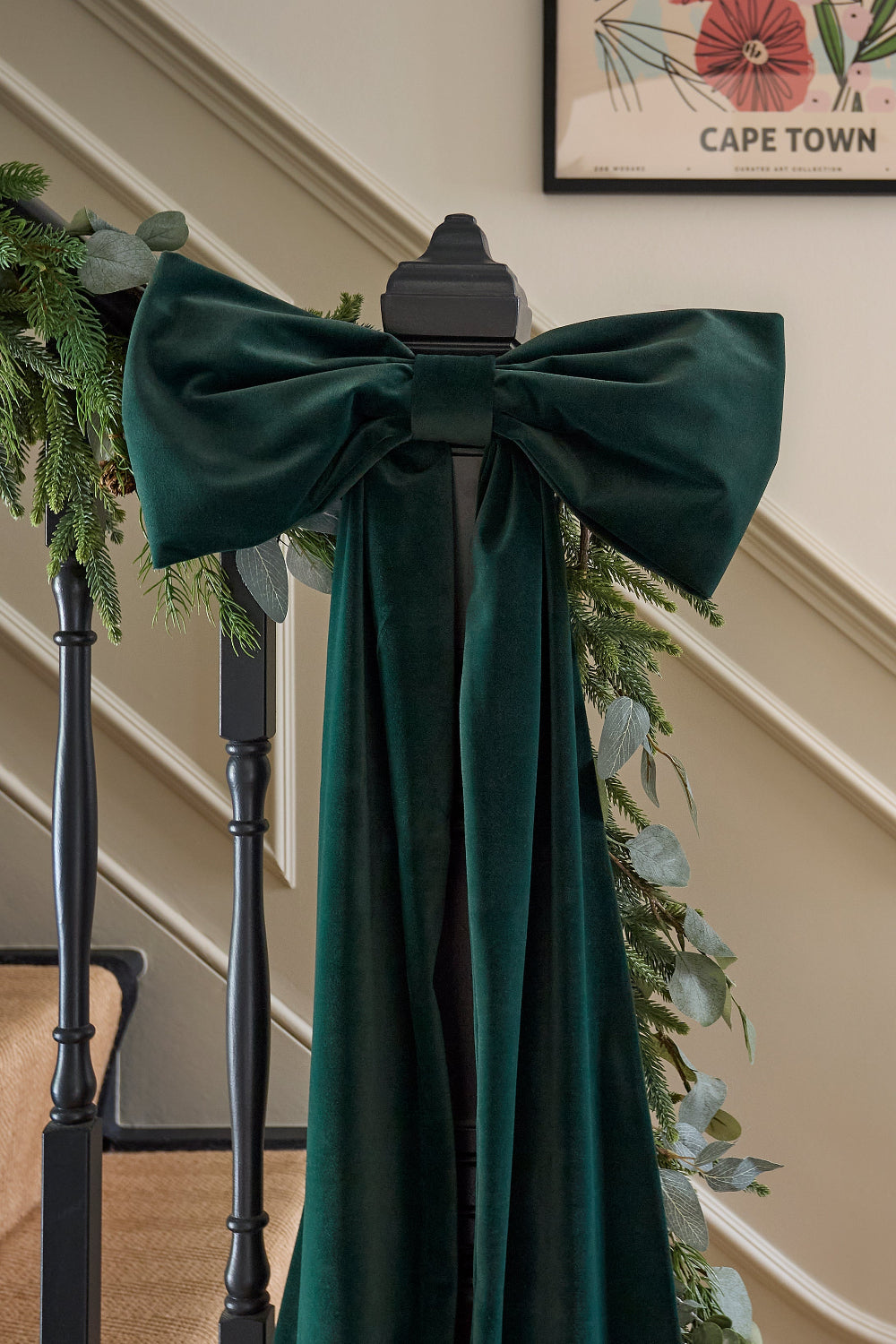 Oversized green velvet bow styled as a statement Christmas staircase decoration