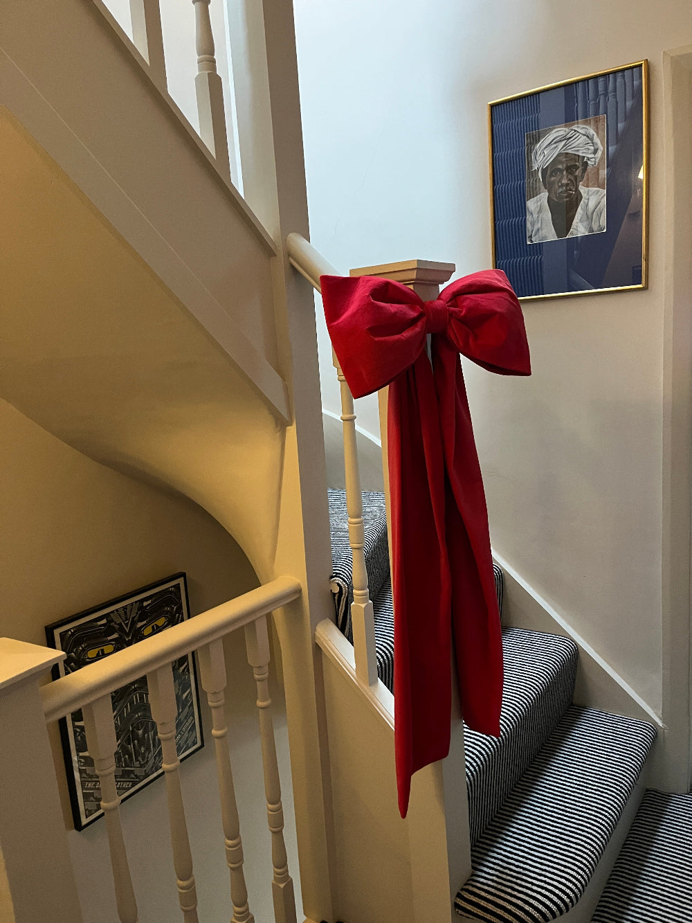 Oversized pink velvet bow used as a colourful Christmas bannister decoration