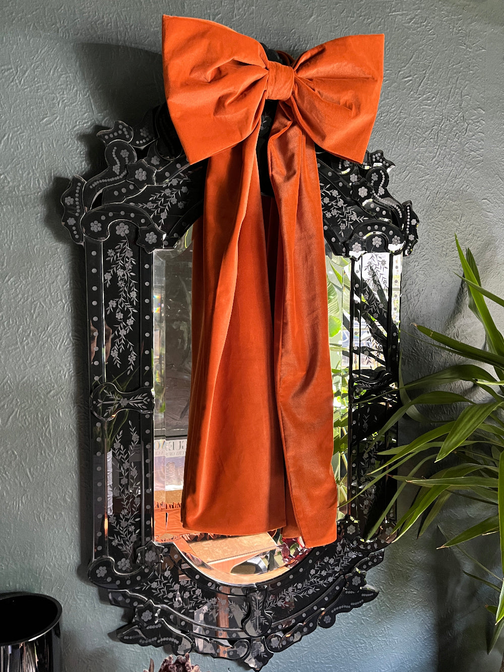 Oversized rust velvet bow styled on an indoor mirror