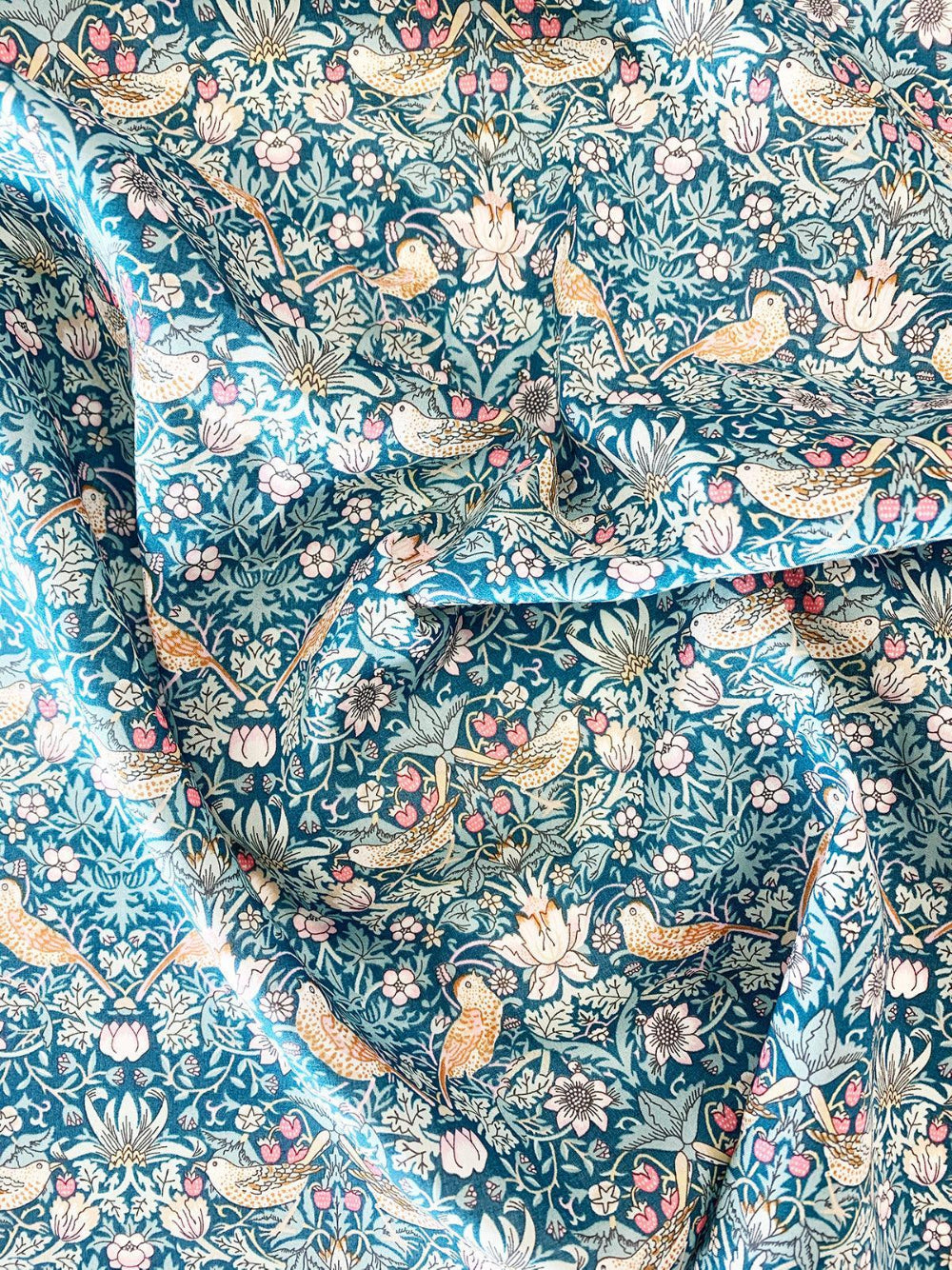 Floral and bird patterned fabric with a blue background william morris strawberry thief