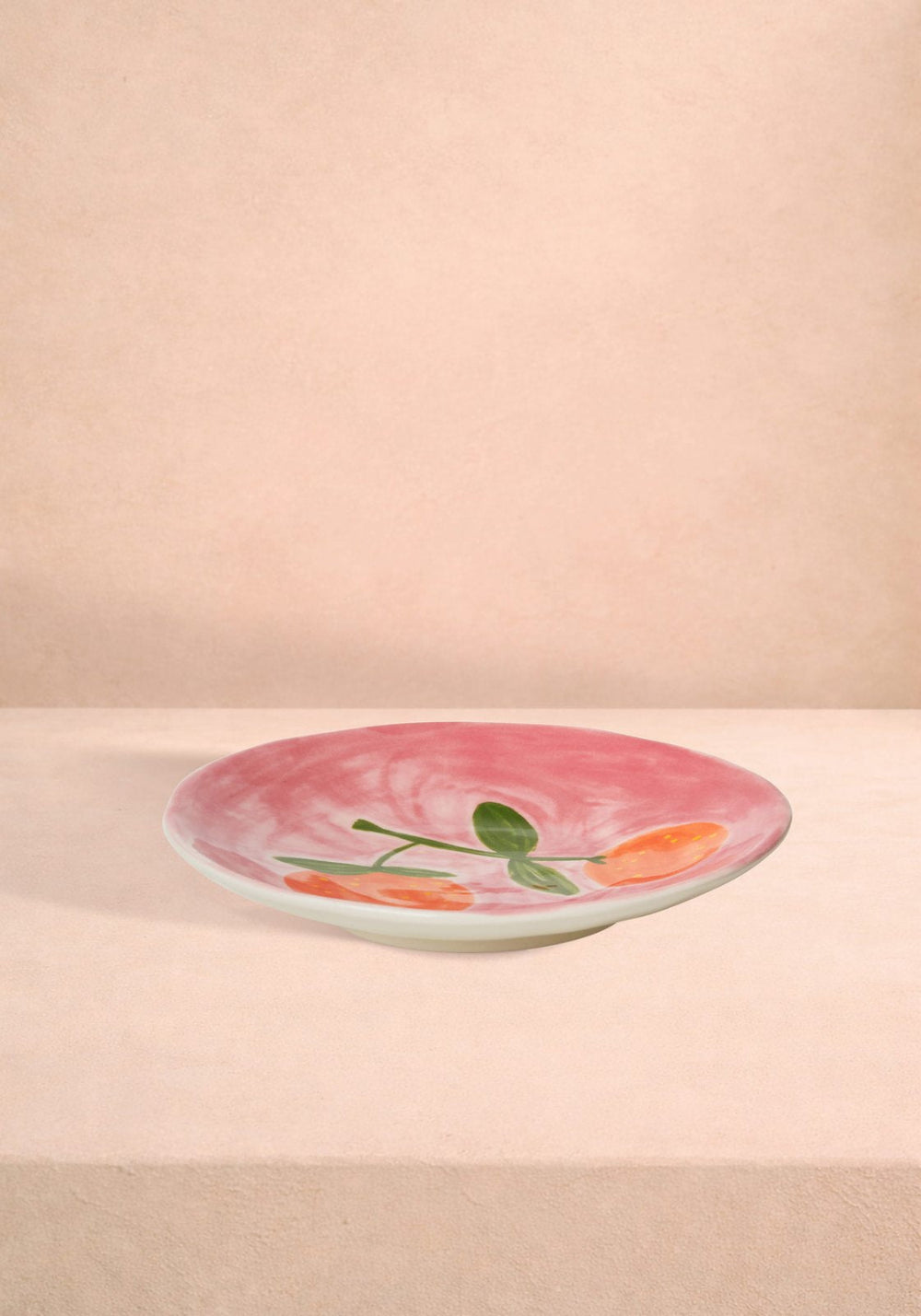 Decorative plate with peach fruit design on a pink background