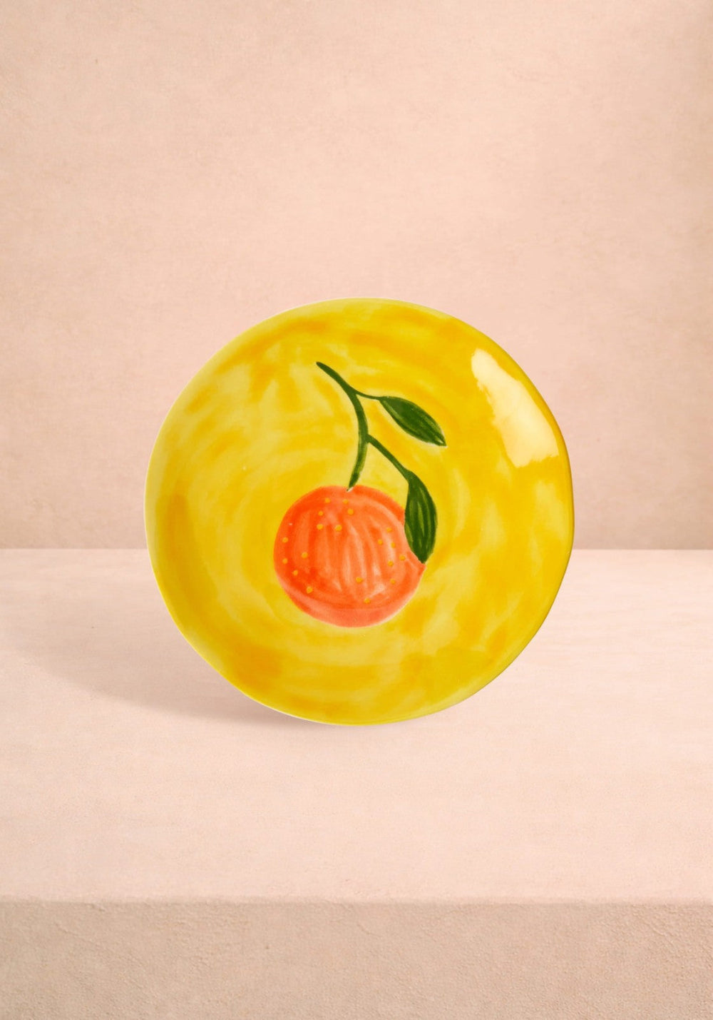 Yellow ceramic plate with a peach design on a beige background