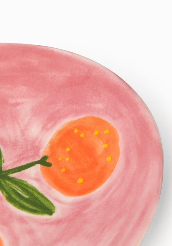 Pink ceramic plate with a peach design on a white background