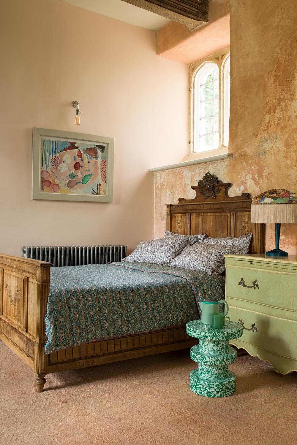 Bedroom with wooden bed, green nightstand, and floral artwork on wall.