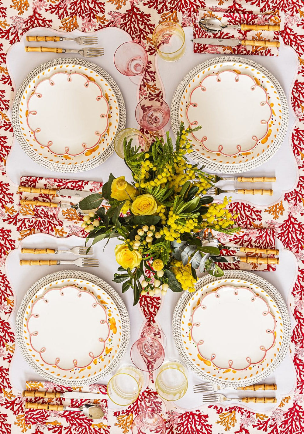 Elegant table setting with floral centerpiece, plates, and cutlery on a patterned tablecloth.