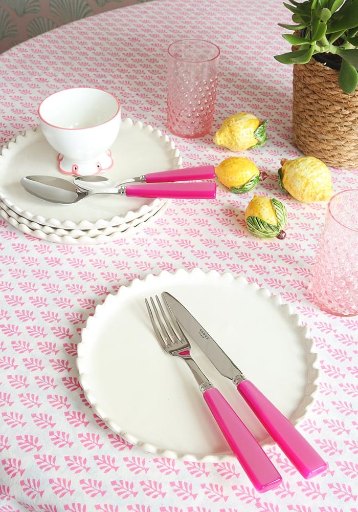 Table setting with pink cutlery on a floral tablecloth