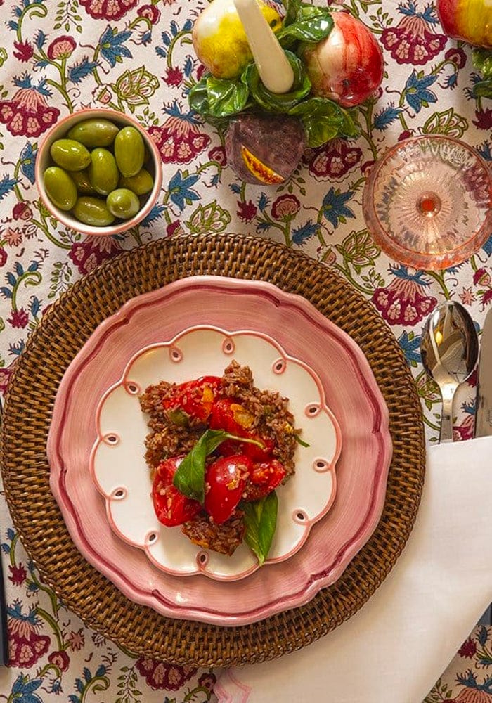 Dinner setting with a pink plate of food on a floral tablecloth