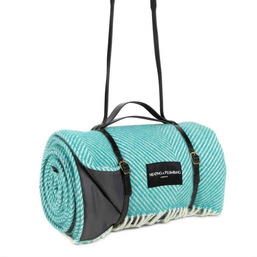 Teal picnic blanket with black straps and a visible brand label on a white background