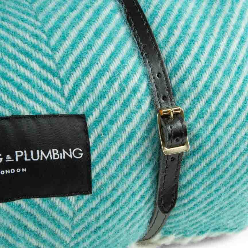 Teal fabric with a black strap and visible brand label on a white background