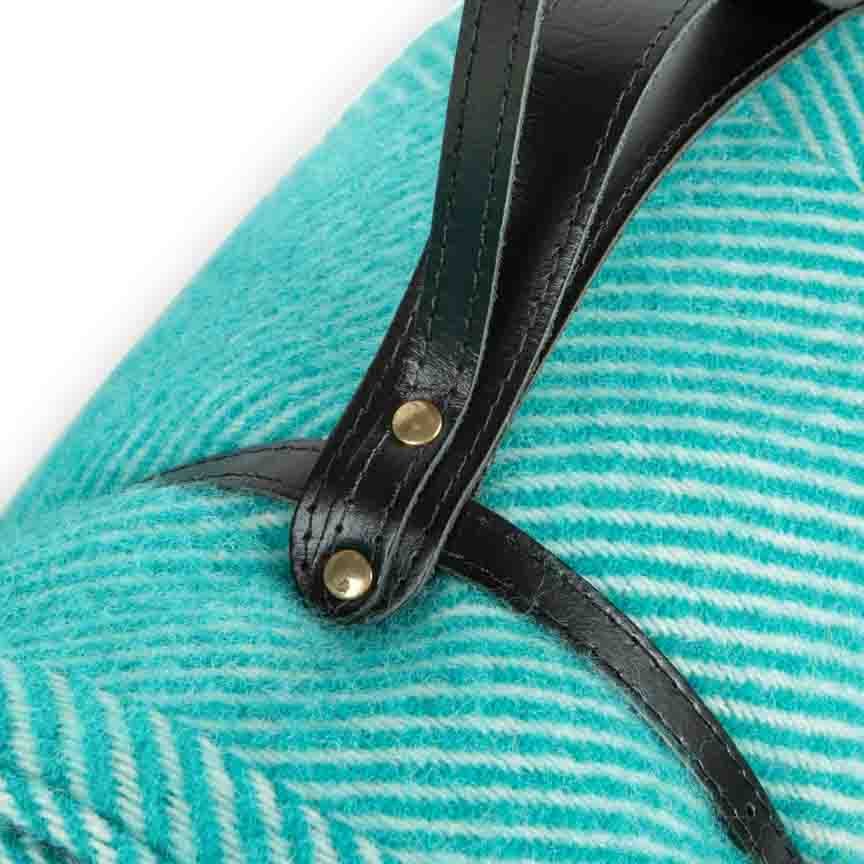 Close-up of a teal sandal with a black strap and gold buckle on a white background