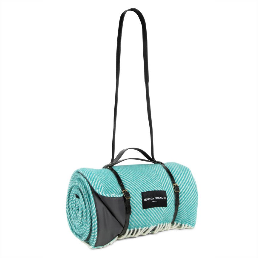 Teal rolled-up rug with black strap on a white background