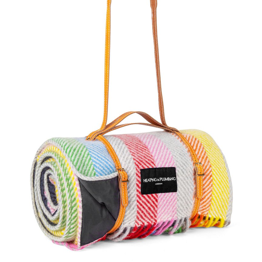 Colourful rolled-up rug with a carrying strap on a white background