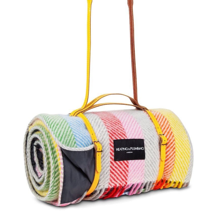 Colourful plaid blanket with a carrying strap on a white background