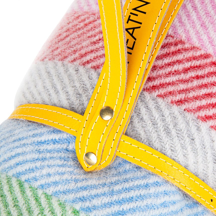 Close-up of a textured blanket with yellow straps and visible branding.