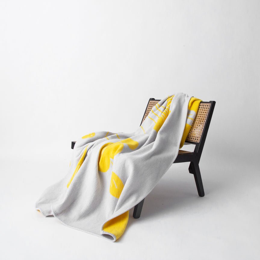 White and yellow blanket draped over a black chair on a white background