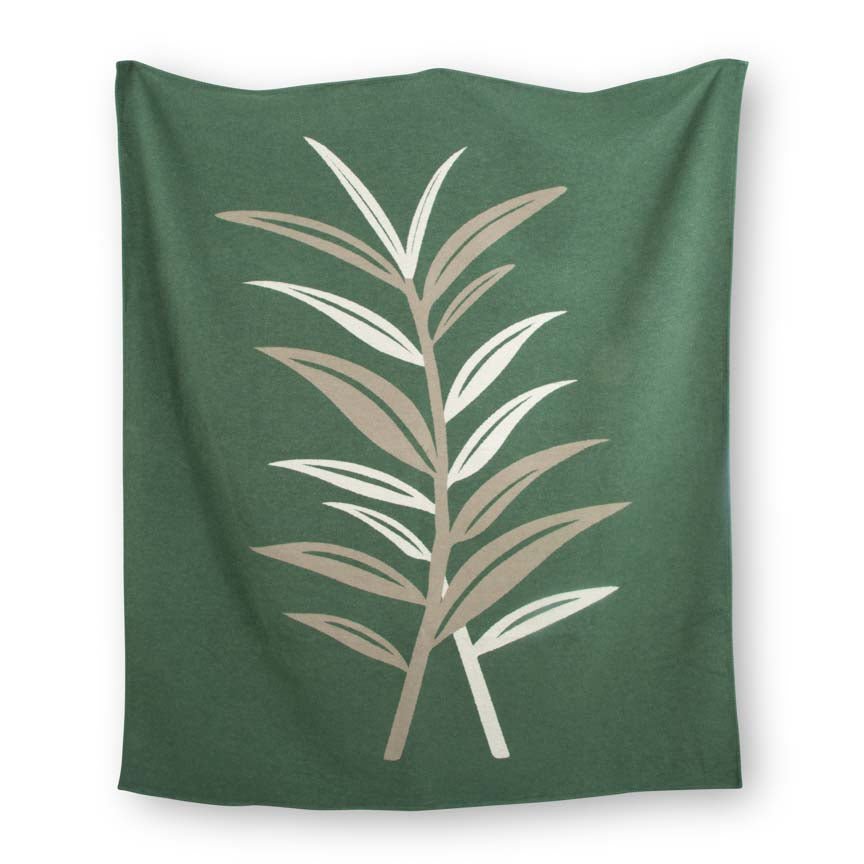 Green blanket with beige leaf pattern on a white background