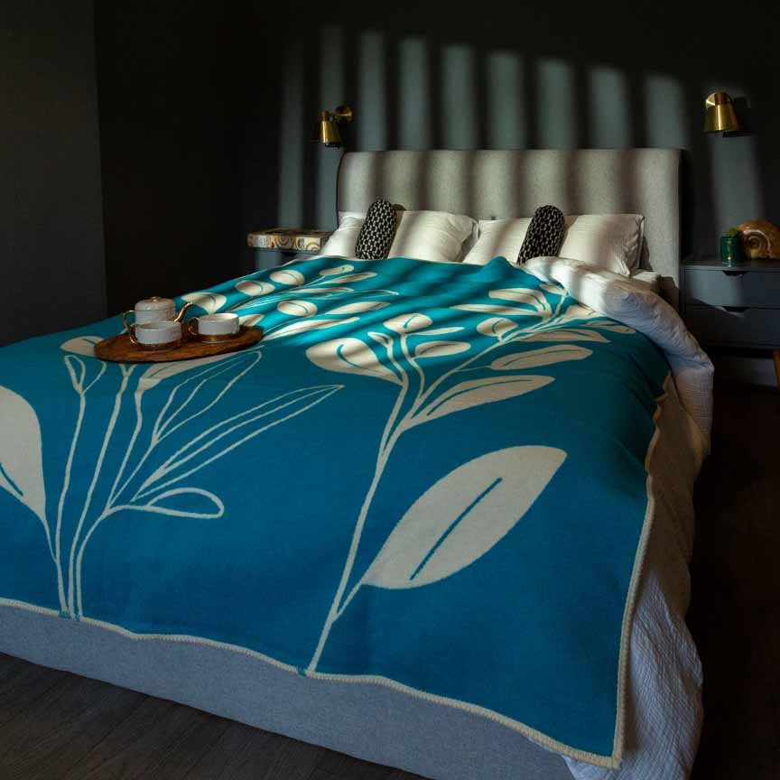 Bed with a blue floral blanket in a dimly lit room