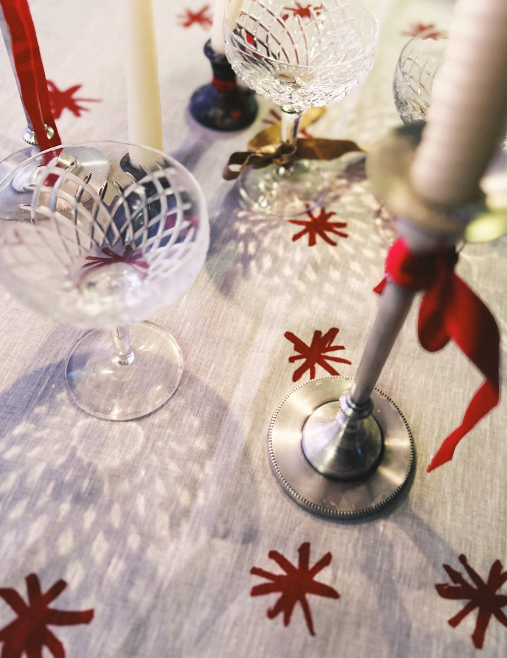 Decorative table setting with wine glasses on a tablecloth featuring red star patterns.