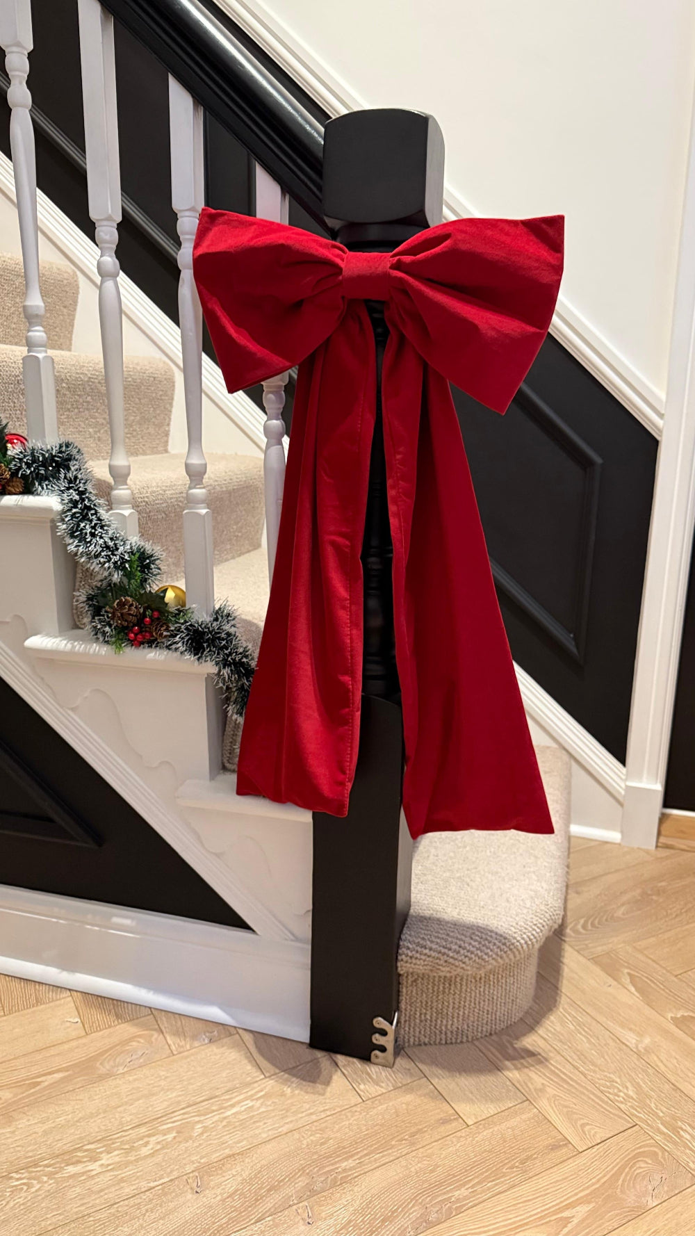 Red velvet Christmas bow styled on a staircase bannister