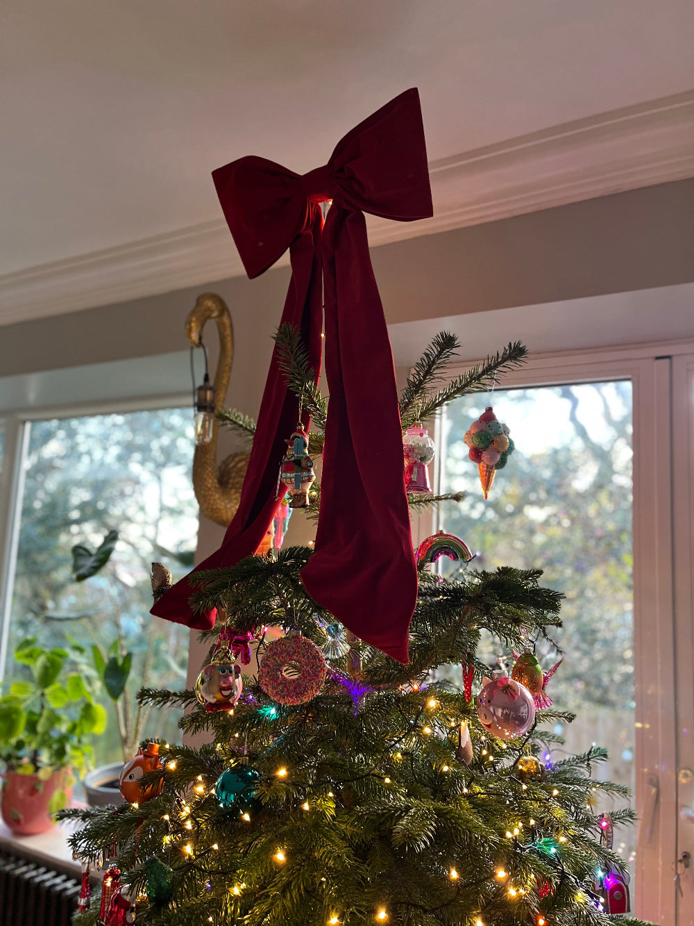 Oversized red velvet bow styled as a Christmas tree topper