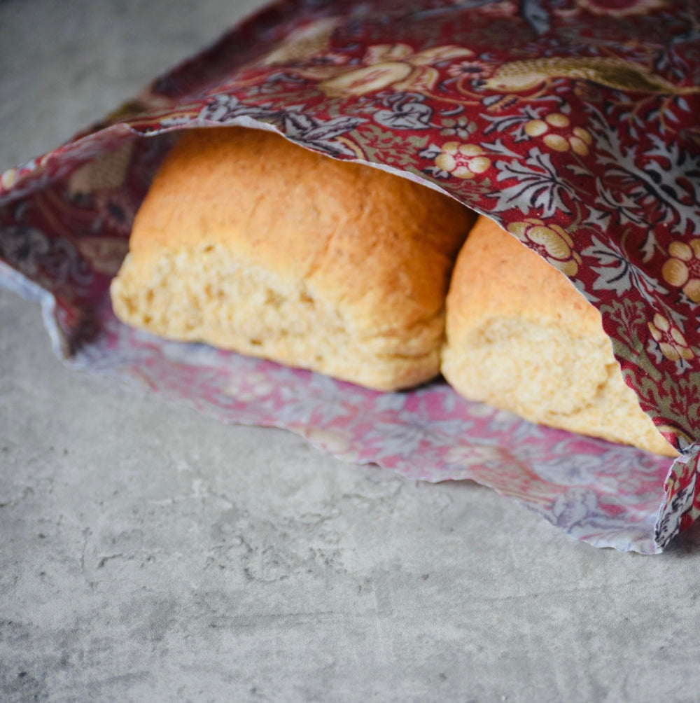 Loaf of bread wrapped in a patterned beeswax wrap on a concrete surface