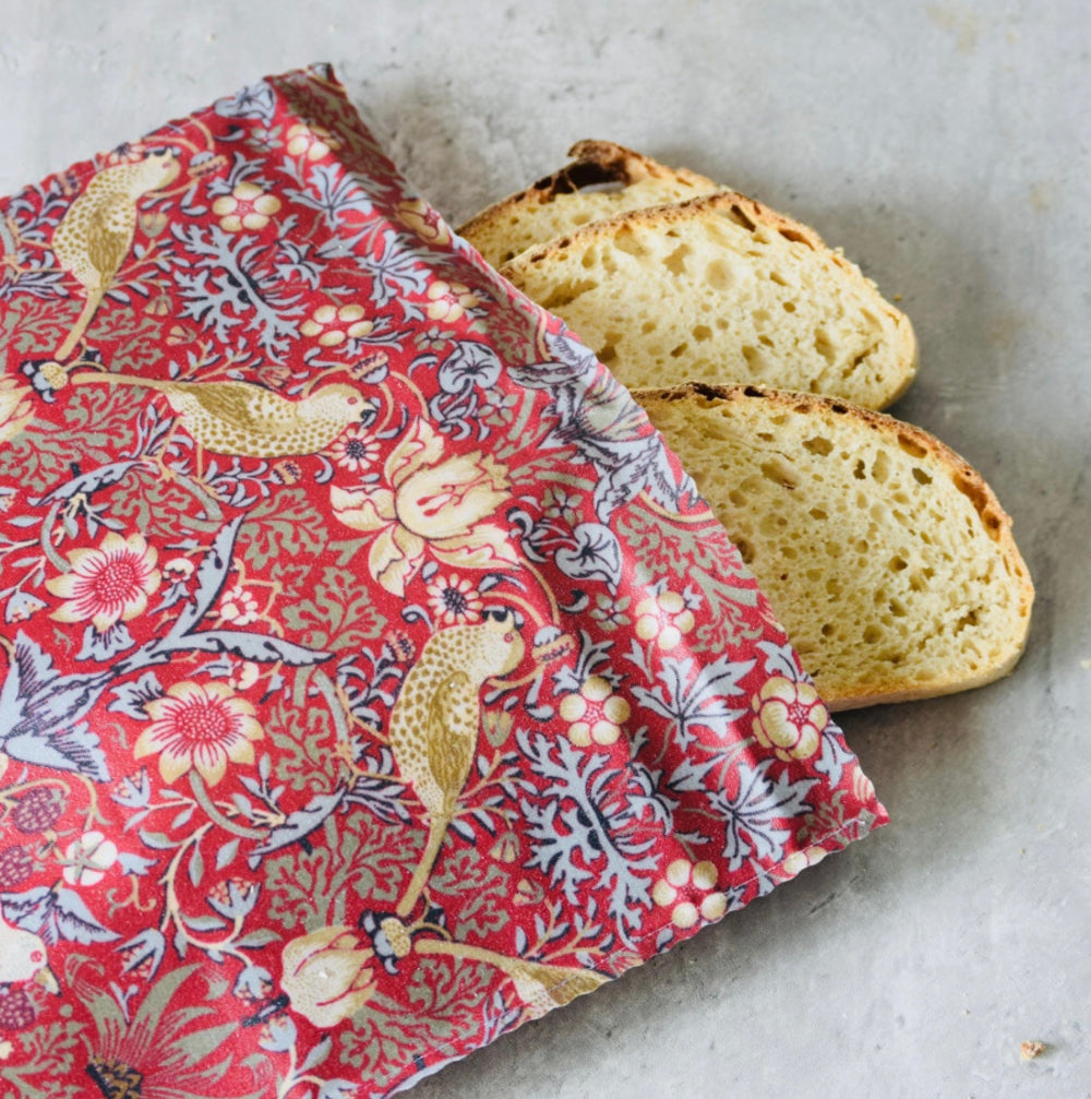 Two slices of bread wrapped in a red floral william morris on a grey surface