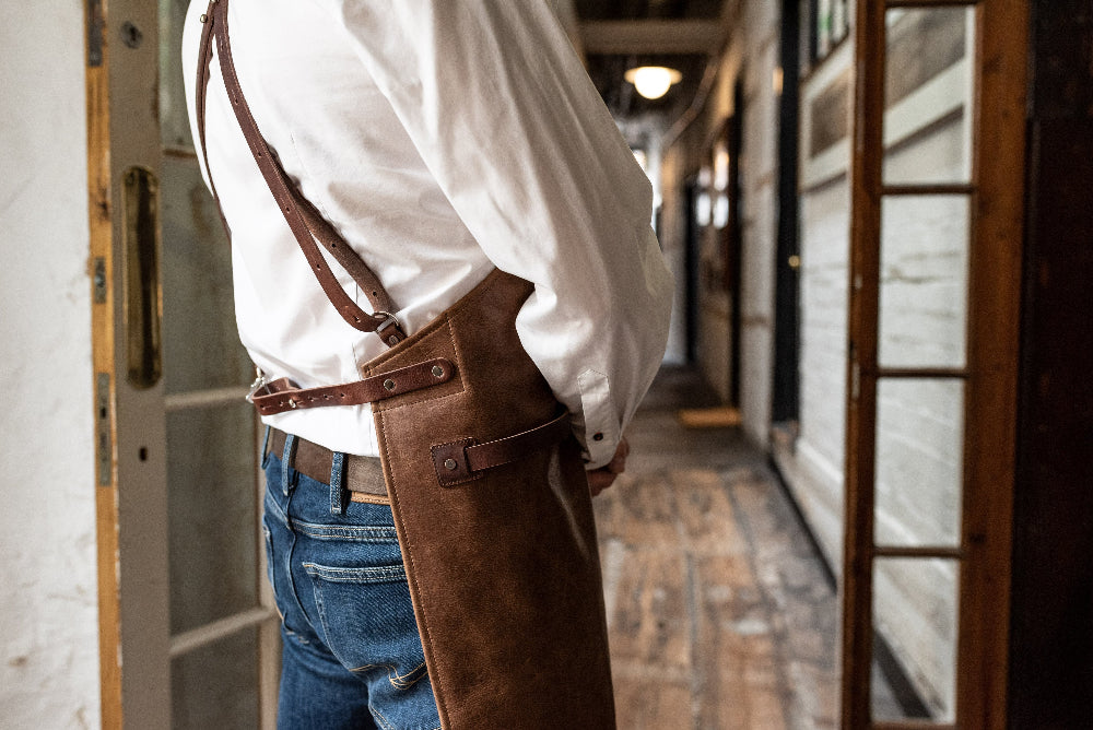Person wearing a white shirt and brown apron in a hallway
