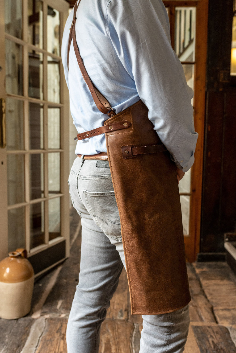 Person wearing a brown leather apron in an indoor setting