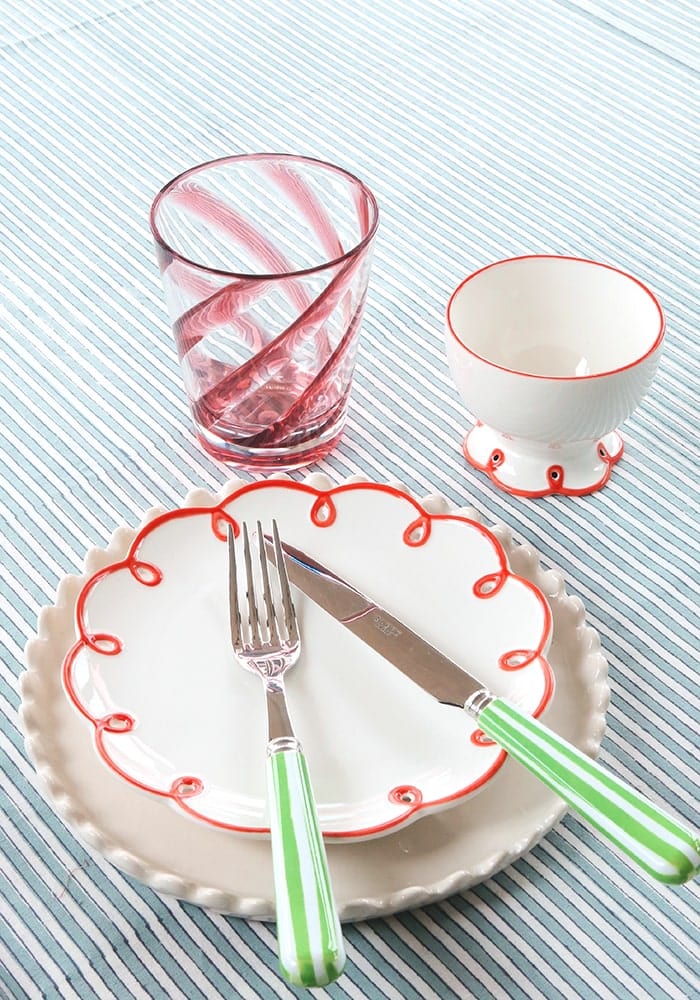 Dinner set with a plate, glass, and cutlery on a striped tablecloth
