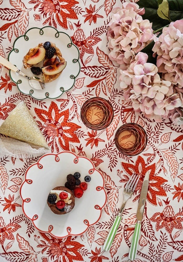 Side Scalloped edge plates with pastries on a patterned tablecloth with flowers.