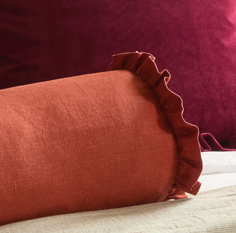 Rust pure linen bolster cushion with gathered ruffle and feather filling