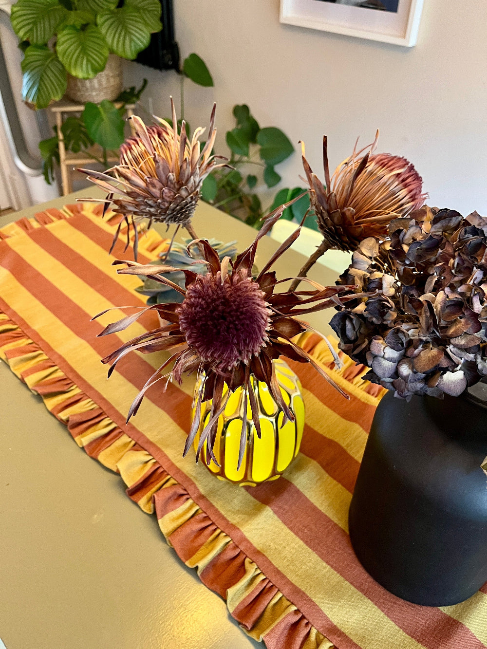 Rust and mustard table runner with decorative objects on a rectangular dining table