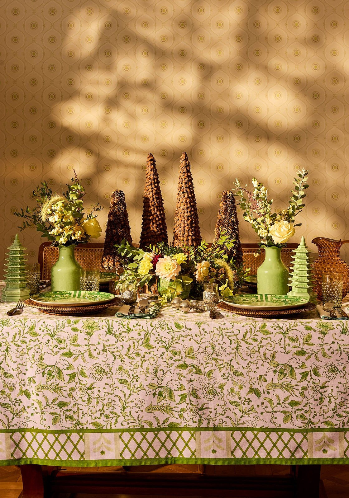 Decorative table setting with green and white tablecloth, vases, and floral arrangements.