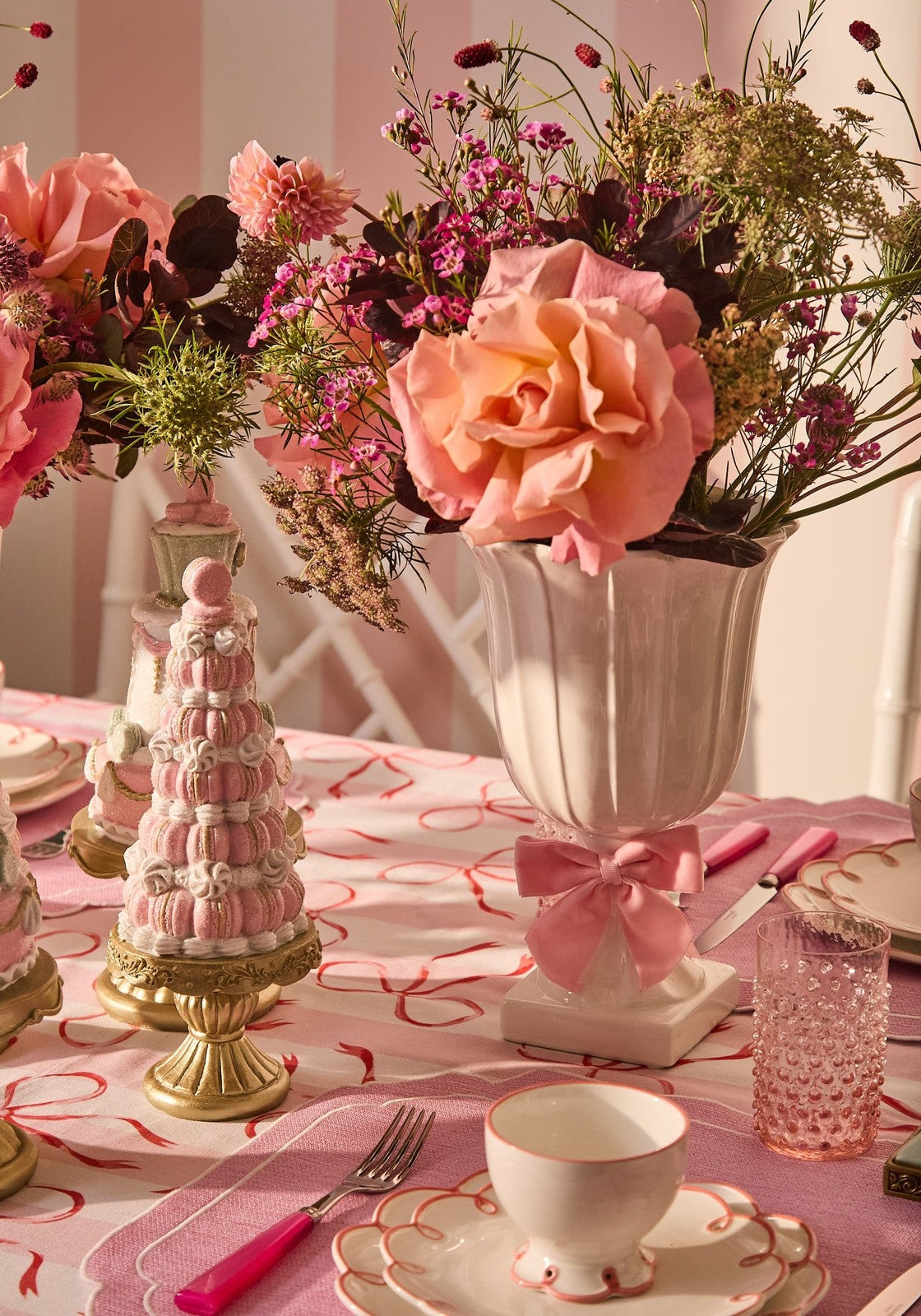 Decorative table setting with pink flowers, teacup, and pink accents on a matching tablecloth.