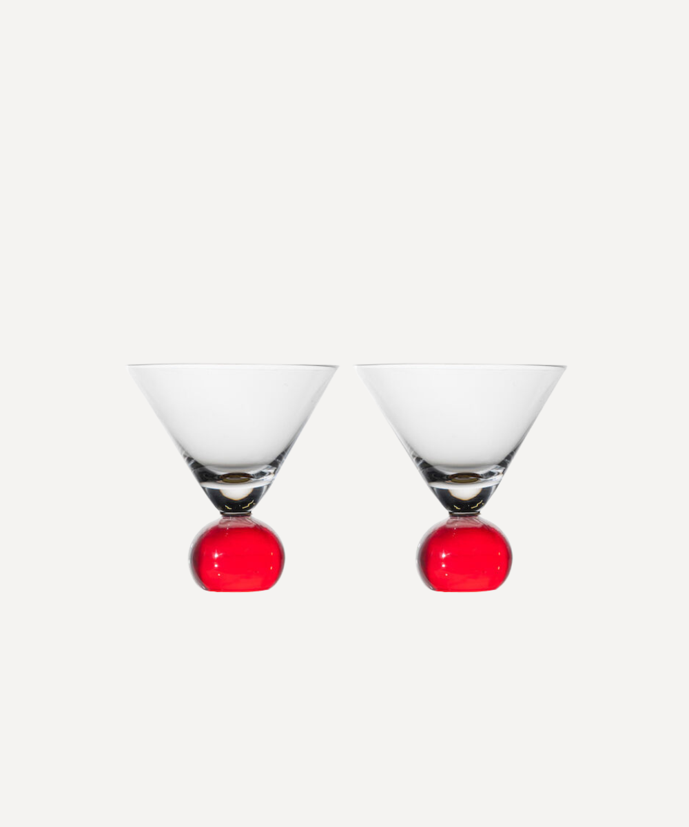 Two martini glasses with red bobble bases on a white background