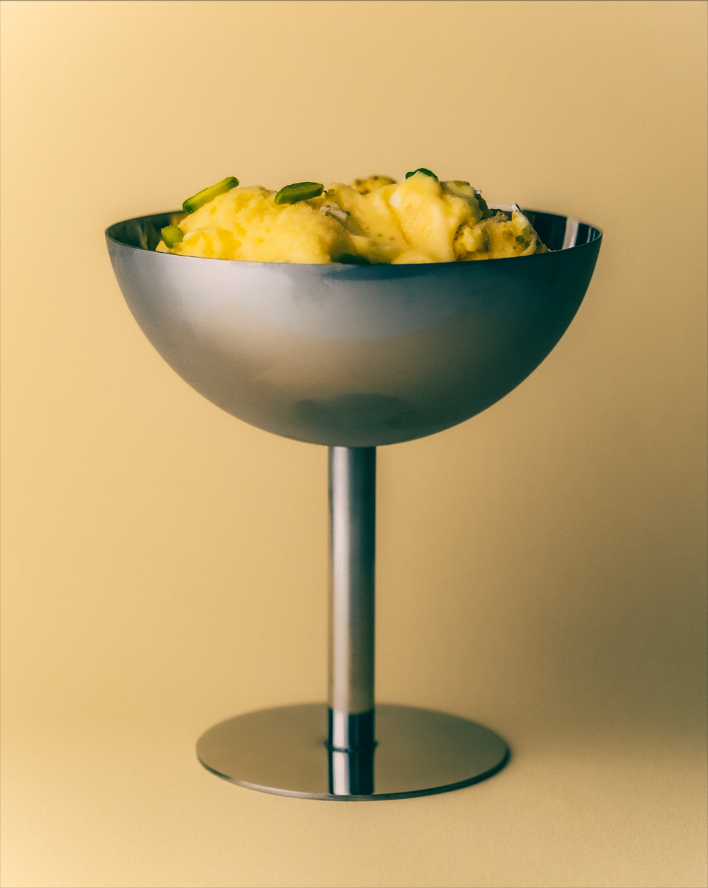 Metallic bowl filled with ice cream on a beige background