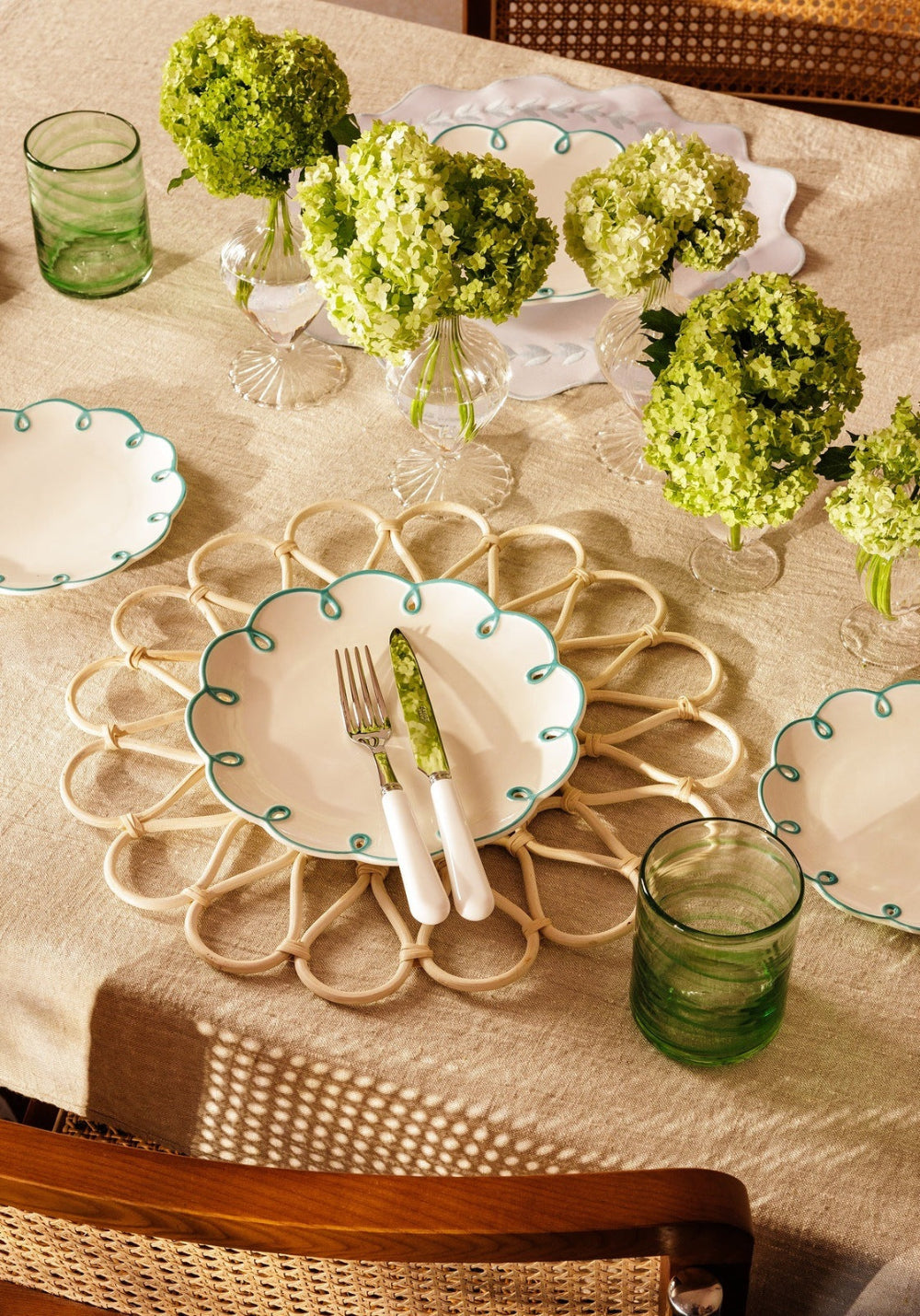Table setting with floral centrepieces, plates, and glasses on a textured tablecloth.